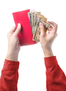Hand holding chinese red envelope with money isolated over white